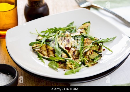 Gegrillte Zucchini mit getrockneten Chili-Flocken, Rucola und Minze-Salat Stockfoto