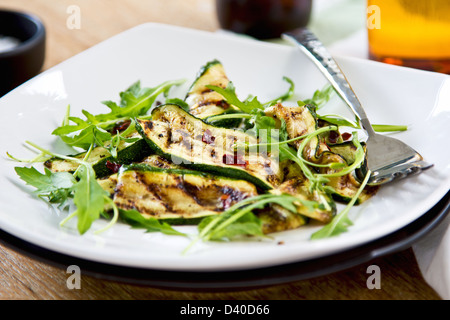 Gegrillte Zucchini mit getrockneten Chili-Flocken, Rucola und Minze-Salat Stockfoto