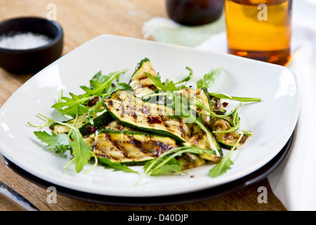 Gegrillte Zucchini mit getrockneten Chili-Flocken, Rucola und Minze-Salat Stockfoto