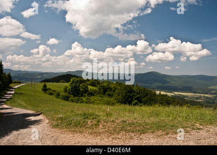 Dziol Hügel auf Slezske Beskydy Berge mit Bergwiese, Bäume, Wanderweg und Moravskoslezske Beskydy Bergkette im Hintergrund Stockfoto