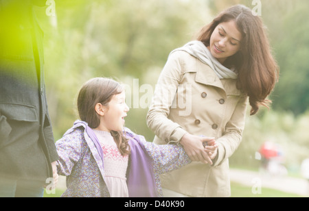 Junge Familie mit drei genießt im Park spazieren. Hübsche Tochter Hand in Hand der Eltern. Glückliche Mädchen im Mittelpunkt. Familie h Stockfoto