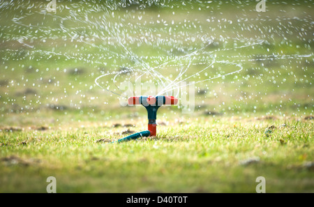 Bewässerungssystem mit Spirale sprüht gehen mit vielen Spritzern und Tropfen fallen auf dem grünen Rasen. Gerät der Bewässerung in gard Stockfoto