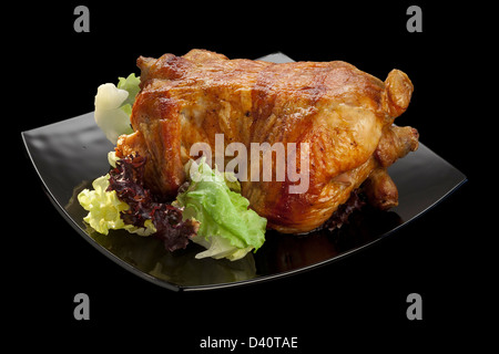 Gegrilltes Hähnchen, serviert mit Blattsalat auf einer schwarzen Platte auf einem schwarzen Hintergrund Stockfoto