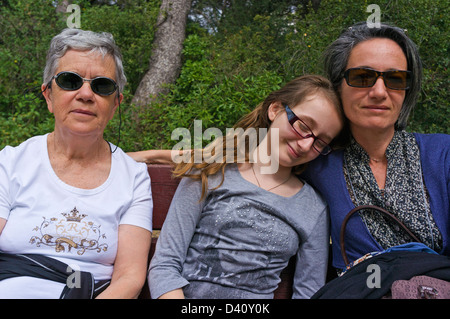 Familiengruppe Porträt - Senior Frau, Tochter und Enkelin ruht auf Bank in einem öffentlichen park Stockfoto