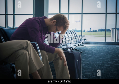 Frustriert kaukasischen Mann sitzen Flughafen Stockfoto