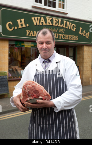 Roger Wakeling Butcher mit Schneiden von Fleisch vor seinem Geschäft im Farncombe Stockfoto