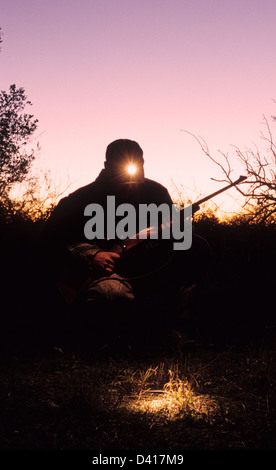 Texas Hirsche Jäger mit einer Stirnlampe, eine Blutspur in der Abenddämmerung zu folgen Stockfoto