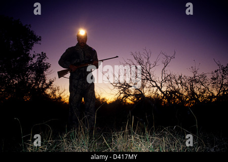 Texas Hirsche Jäger mit einer Stirnlampe, eine Blutspur in der Abenddämmerung zu folgen Stockfoto