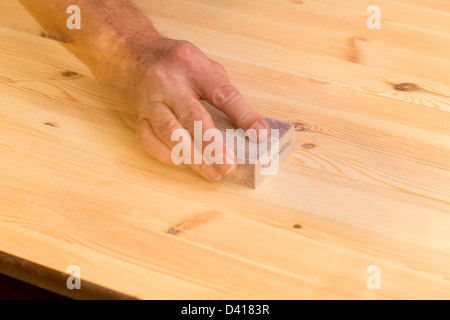 Mann reiben Schleifblock auf Kiefer Boden oder Tisch mit Ghosting Bewegung vorschlagen Stockfoto