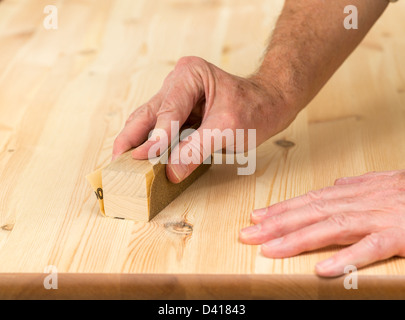 Mann mit einem Schleifblock auf Kiefer Boden oder Tisch Oberfläche Schleifen Stockfoto