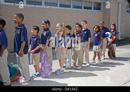 Grundschule in Uniformen warten in der Schlange im Freien an der Schule in Louisiana Rennen Kinder gemischt Stockfoto