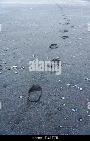 Fußspuren im schwarzen vulkanischen Sandstrand bei Vík Í Mýrdal Island Stockfoto