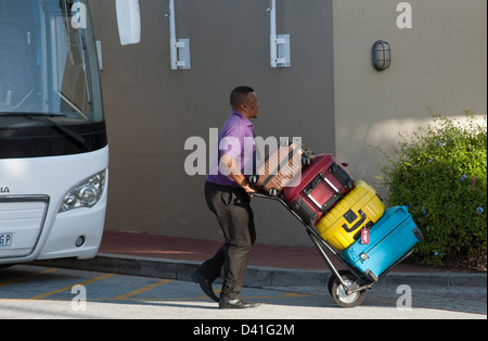 Porter mit Gastes Koffer auf einem Wagen. Entladung von einem Tour-Bus in Südafrika Stockfoto