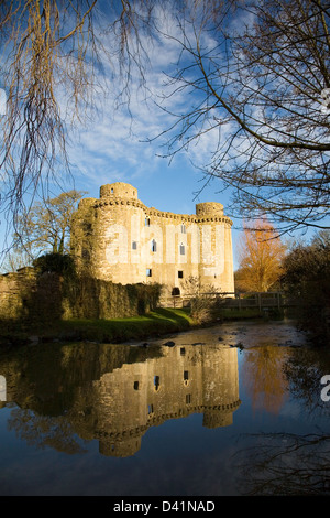 Burgruine in Nunney, Somerset, UK im warmen Morgenlicht mit Reflexion in den Fluss. Stockfoto