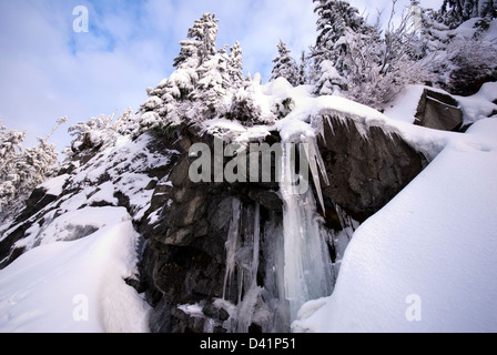 Eiszapfen hängen von den Felsen am Rande eines Berges im winter Stockfoto