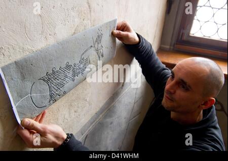 Frank Schmidt hält eine Replik einer Zeichnung einer Kanone unter dem ursprünglichen Putzes Rochlitz Schloss Rochlitz, Deutschland, 28. Februar 2013. Spätmittelalterlichen Putz Zeichnungen aus dem 15. Jahrhundert wurden bei der Restaurierung Schloss Rochlitz gefunden. Foto: Marc Tirl Stockfoto