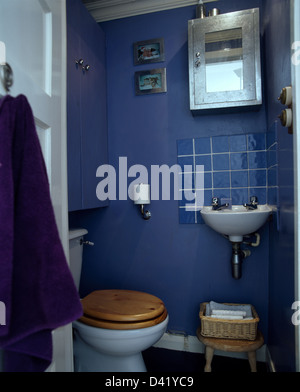 Spiegelschrank auf Wand über Blau gekachelt Splash-Rücken und kleine Wand-Becken in blaue Garderobe Stockfoto