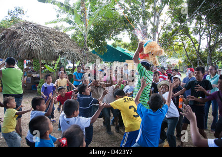 Ein gebrochenen offenen Pinata und ein Kerl Duschen den Inhalt wie Süßigkeiten und Spielzeug unter den Kindern bei einem Festival in Panama. Stockfoto