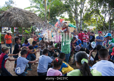 Ein gebrochenen offenen Pinata und ein Kerl Duschen den Inhalt wie Süßigkeiten und Spielzeug unter den Kindern bei einem Festival in Panama. Stockfoto