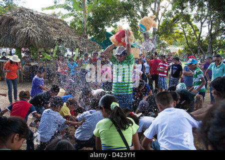 Ein gebrochenen offenen Pinata und ein Kerl Duschen den Inhalt wie Süßigkeiten und Spielzeug unter den Kindern bei einem Festival in Panama. Stockfoto