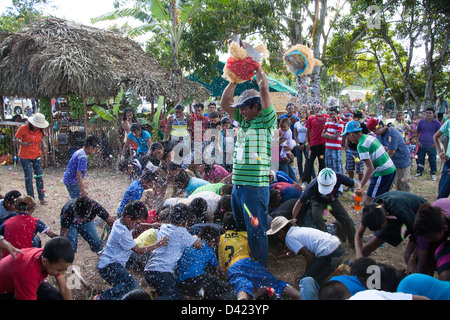 Ein gebrochenen offenen Pinata und ein Kerl Duschen den Inhalt wie Süßigkeiten und Spielzeug unter den Kindern bei einem Festival in Panama. Stockfoto