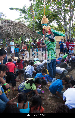 Ein gebrochenen offenen Pinata und ein Kerl Duschen den Inhalt wie Süßigkeiten und Spielzeug unter den Kindern bei einem Festival in Panama. Stockfoto