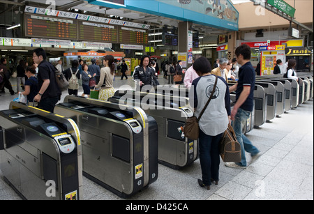 Pendler auf der Durchreise elektronische Einlasspforten auf ihrem Weg an die Bahnsteige im Bahnhof Ueno, Tokio. Stockfoto