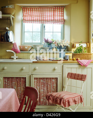 Roten aufgegebenes Blind auf Fenster oben einsinken montierten Einheiten mit roten + weißen Vorhängen im Cottage-Küche Stockfoto