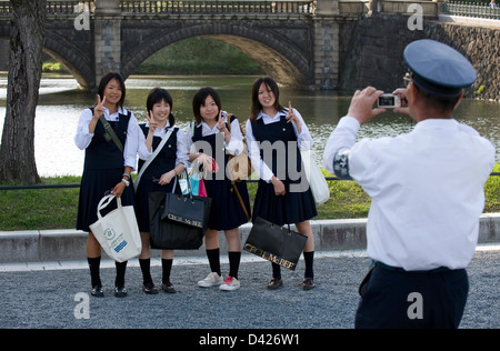 Security Guard unter Erinnerungsfoto von High-School-Mädchen an Tokios berühmten Imperial Palace Nijubashi Brücke. Stockfoto