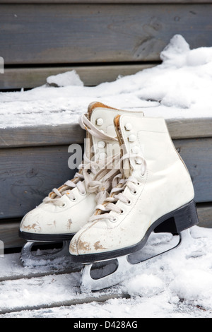 Paar weiße alte Schlittschuhe auf verschneiten Holztreppen Stockfoto