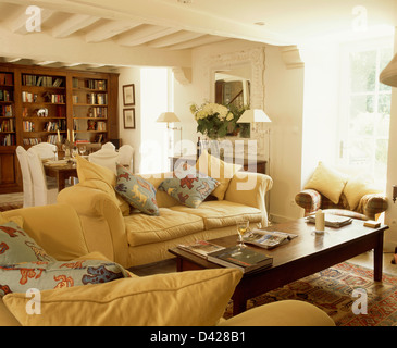 Gelben Sofas mit Tier-gemusterten Kissen Antik Kaffeetisch in weiße französische Land-Wohnzimmer mit Essbereich Stockfoto