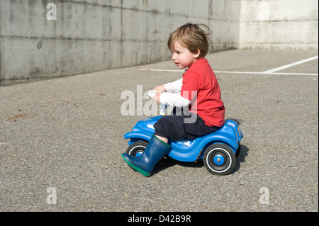 Carabietta, Schweiz, setzt sich Young mit einem Bobby Car Stockfoto