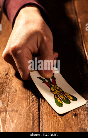 Hand hält eine neapolitanische Spielkarte, die drei Vereine Stockfoto