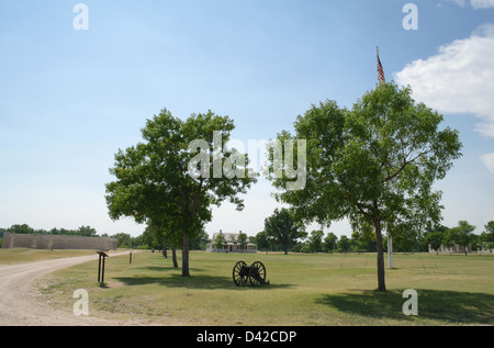 Blauer Himmelsblick auf "Kommandierender Offizier Haus", alte Kanone zwischen Bäumen, grünen Rasen Exerzierplatz, Fort Laramie, Wyoming, USA Stockfoto