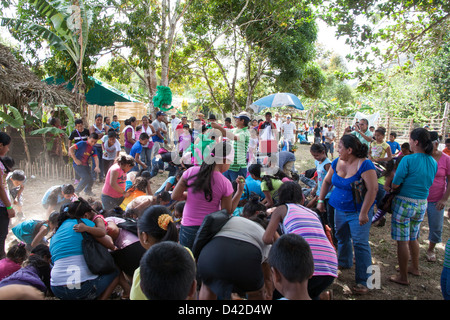 Ein gebrochenen offenen Pinata und ein Kerl Duschen den Inhalt wie Süßigkeiten und Spielzeug unter den Kindern bei einem Festival in Panama. Stockfoto