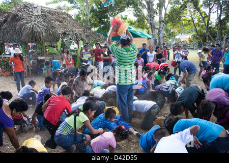 Ein gebrochenen offenen Pinata und ein Kerl Duschen den Inhalt wie Süßigkeiten und Spielzeug unter den Kindern bei einem Festival in Panama. Stockfoto