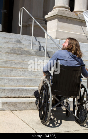 Behinderte Menschen im Rollstuhl sucht eine Rampe zum Zugriff auf ein öffentliches Gebäudeeingang. Stockfoto