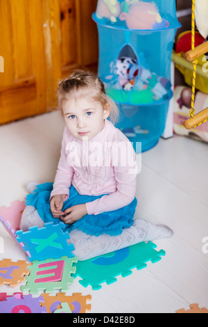 Niedliche kleine Mädchen spielen Rätsel auf der Etage Stockfoto