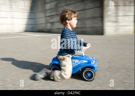 Carabietta, Schweiz, setzt sich Young mit einem Bobby Car Stockfoto