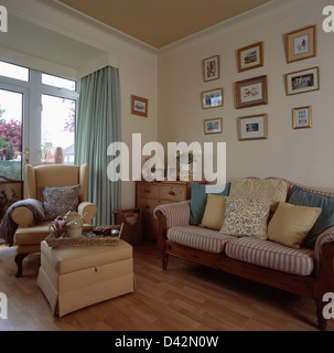 Holzsofa mit gestreiften und schlichte Kissen in Wirtschaft-Stil Wohnzimmer mit Ottoman Hocker und Stuhl vor dem Fenster Stockfoto