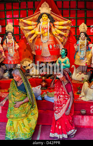 Zwei Frauen in Saris vervollständigen ihre Puja an die Göttin Durga Pandals, display, in der Nähe von Chowringhee, Kolkata, Indien während Durga Puja. Stockfoto