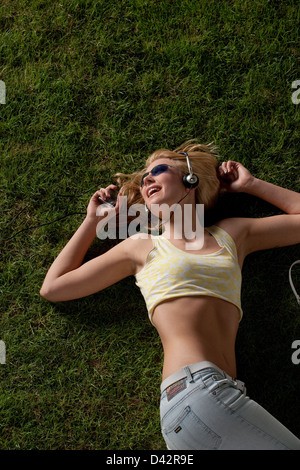 Freiburg, Deutschland, eine junge Frau auf den Rasen und hört Musik entspannen Stockfoto