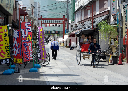 Eine Familie, eine Fahrt in ein Jinrikisha (Rikscha) durch die Straßen von Asakusa, Tokio, dem alten Vergnügungsviertel. Stockfoto