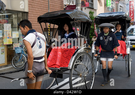 Touristen, die eine Fahrt in ein Jinrikisha (Rikscha) durch die Straßen von Asakusa, Tokio, dem alten Vergnügungsviertel. Stockfoto