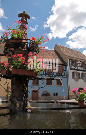 Dorfbrunnen mit mit blauen Fachwerkhaus im Elsass/Frankreich Stockfoto
