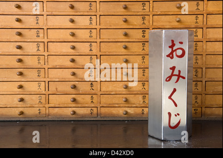 Wählen Sie einen nummerierten Stock aus dem Behälter um das Omikuji Glück in der passenden Nummer Schublade am Sensoji-Tempel in Tokio zu finden Stockfoto