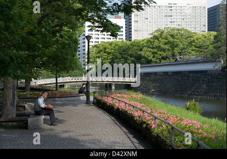 Entspannen Sie in einem Park von Rosa Azaleen mit Blick auf Takebashi Brücke über Graben der alten Burg Edo, jetzt Kaiserpalast in Tokio Stockfoto