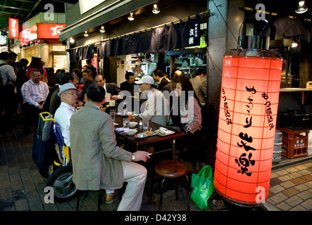 Gäste genießen ein spätes Abendessen im Bürgersteig Restaurant unter Gleisanlagen in der Unterhaltung Bezirk Okachimachi, Tokio. Stockfoto