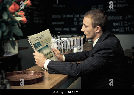 ein Geschäftsmann allein in einer Kneipe, Lesen von Nachrichten nicht so frisch. Hinweis: Papier ist fiktiv, Foto auf der Titelseite ist auch durch mich urheberrechtlich geschützt. Stockfoto
