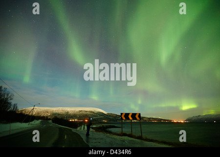 einsamer Fotograf macht Fotos von wirbelnden Nordlicht Aurora Borealis über Fjord in der Nähe von Tromsø in Norwegen Nordeuropa Stockfoto